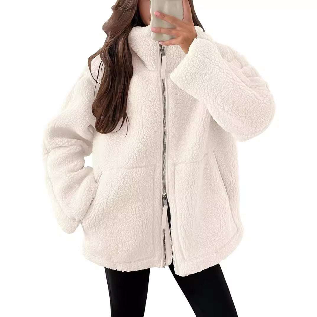 Women wearing white fluffy winter lapel zip-up coat with pockets and black pants taking mirror selfie