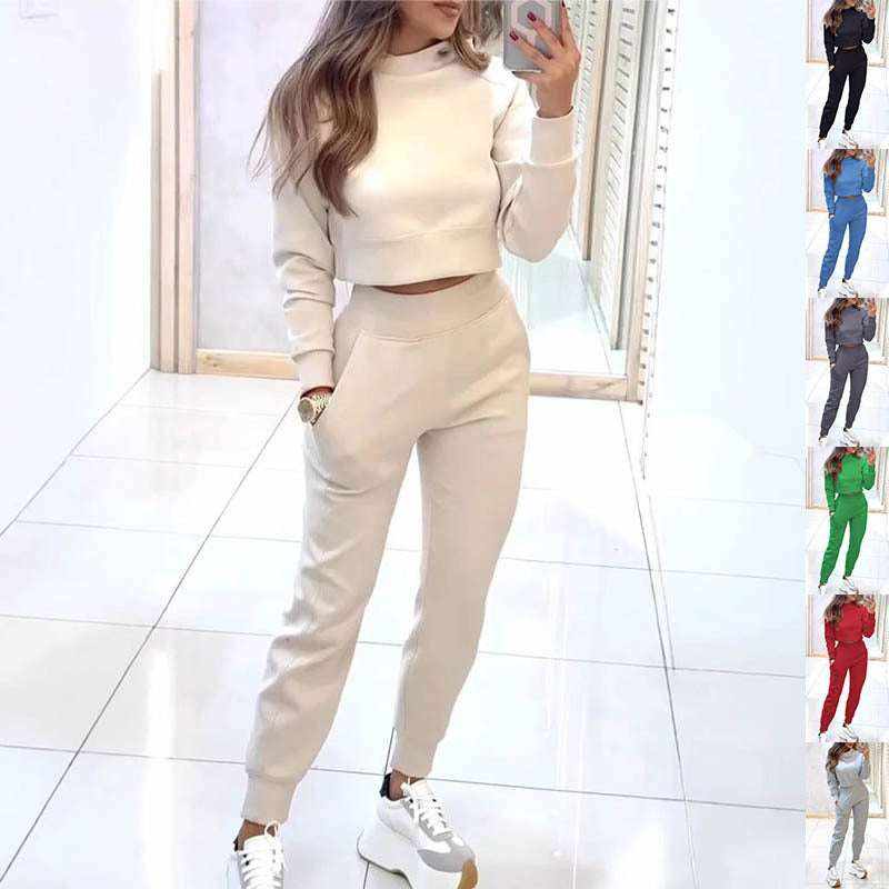 Woman wearing a beige suit fashion pullover with matching pants and white sneakers in a bright room mirror selfie