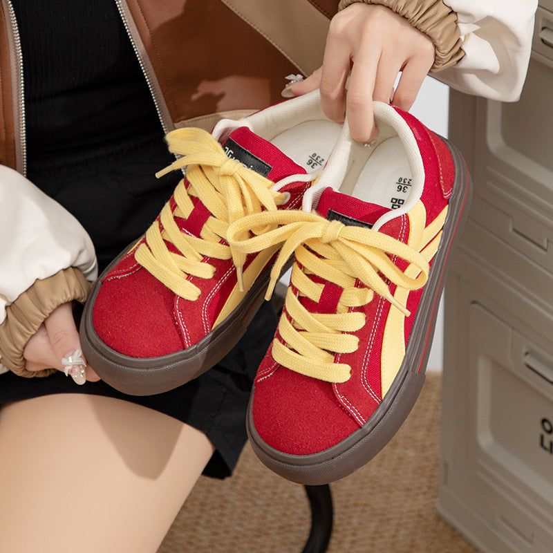 Red and yellow lightweight sneakers with brown soles held by person