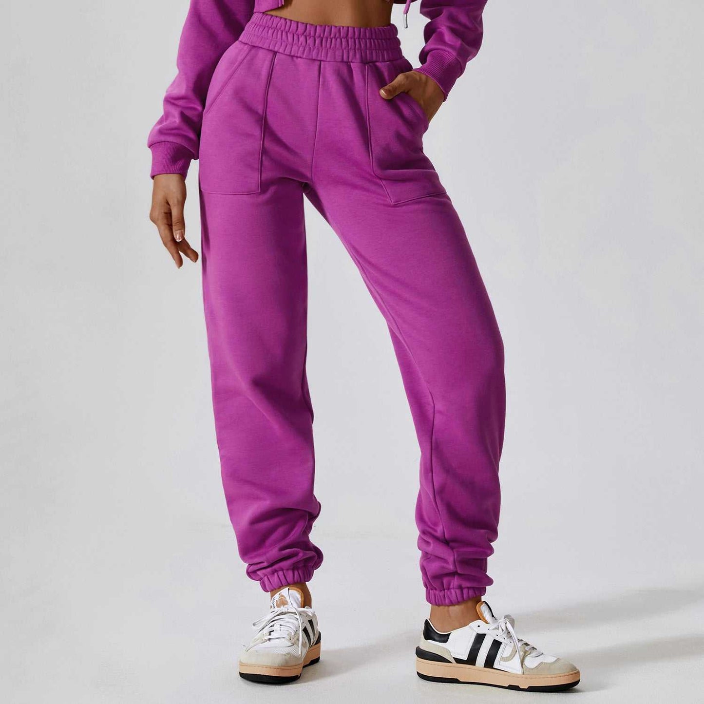 Woman wearing purple Polar Velvet Sweatpants with elastic waistband and cuffs, paired with white sneakers.