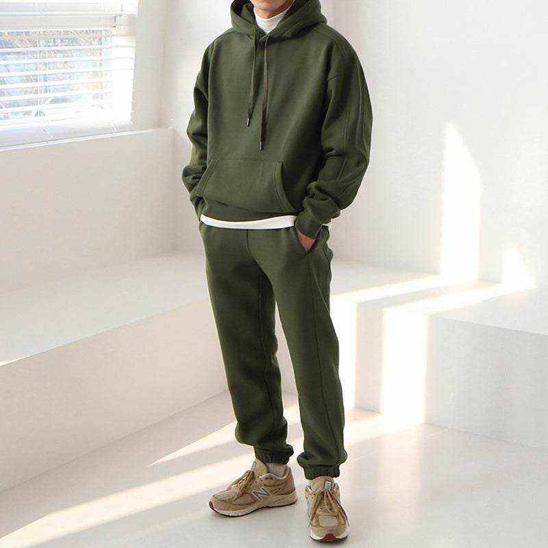 Man wearing olive green loose sportswear hoodie and pants in a bright room