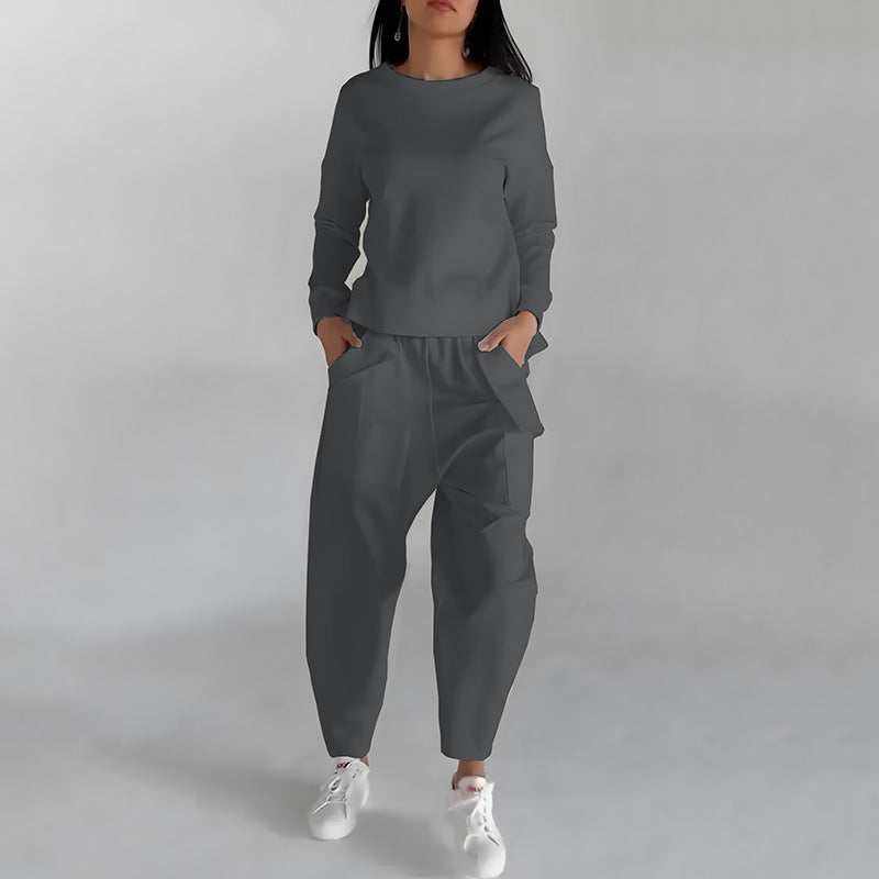 Woman wearing a gray fashion sweatshirt top and matching pants with white sneakers.