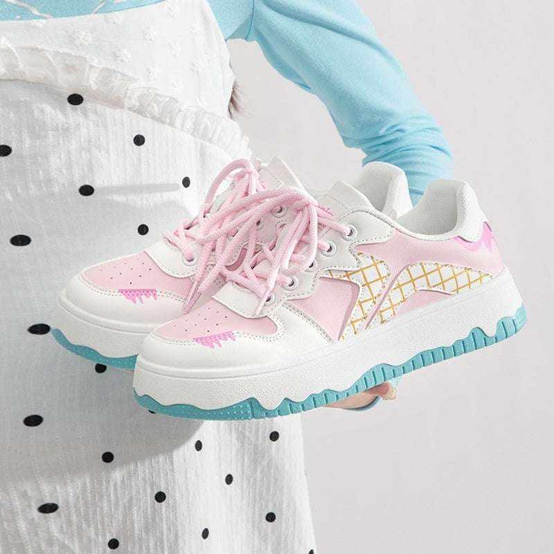Pink and white platform sneakers with blue soles and lace-up design held by a person wearing a blue shirt and polka dot apron