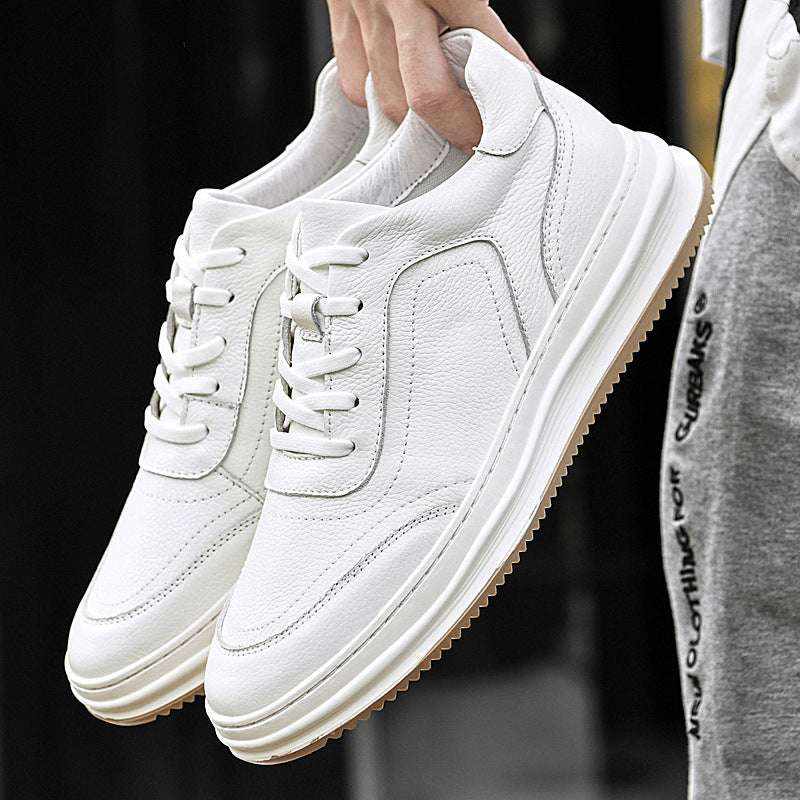 Pair of white Korean trendy sneakers with a gum sole held in hand against a dark background