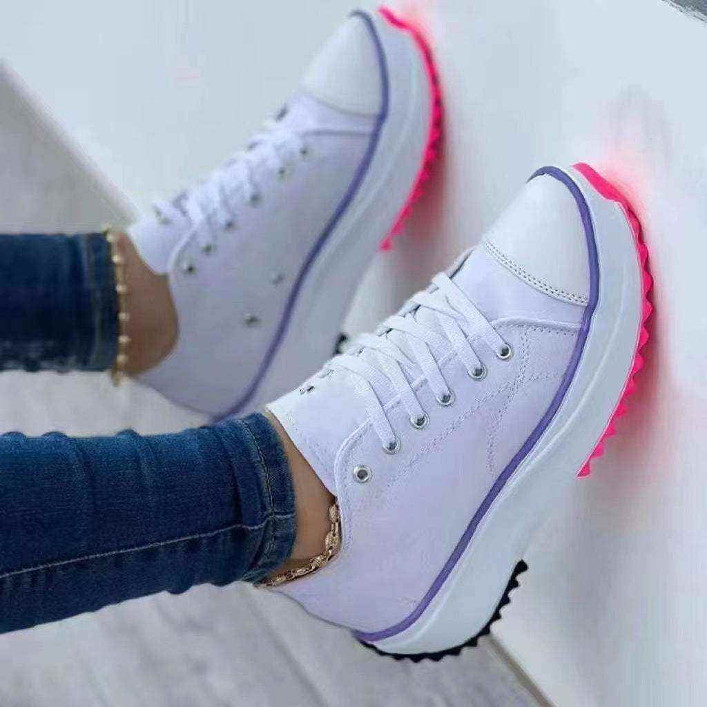 White canvas top sneakers with purple trim and glowing pink soles worn with jeans