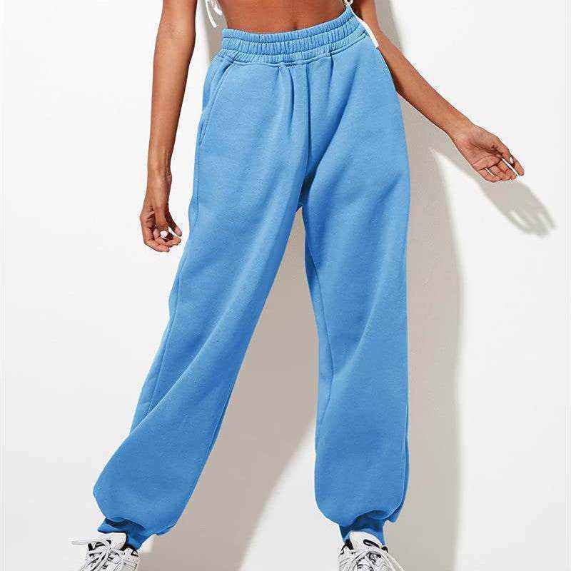 woman wearing blue jogger sweatshirt pants and white sneakers against white background