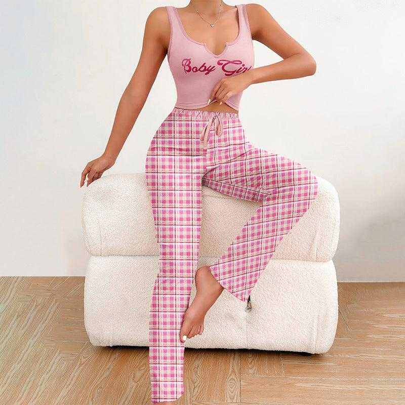 Woman wearing casual pink pajamas with plaid pants and pink tank top sitting on white couch