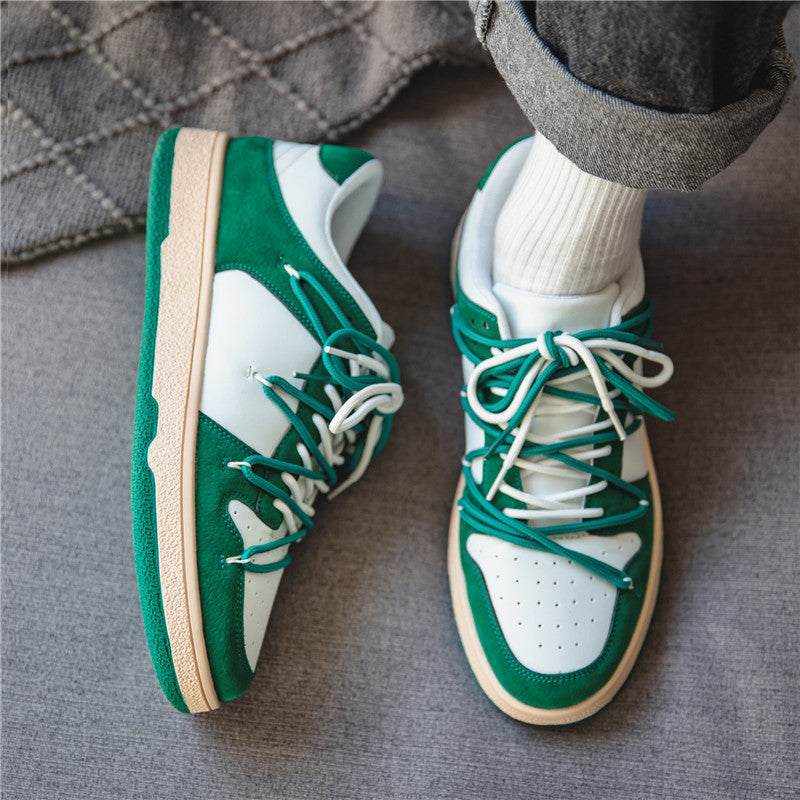 Green and white platform sneaker with beige sole worn with white socks and rolled jeans