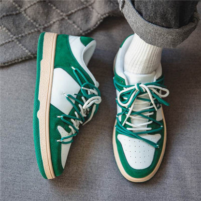 Green and white platform sneakers with thick beige soles worn with white socks and gray pants
