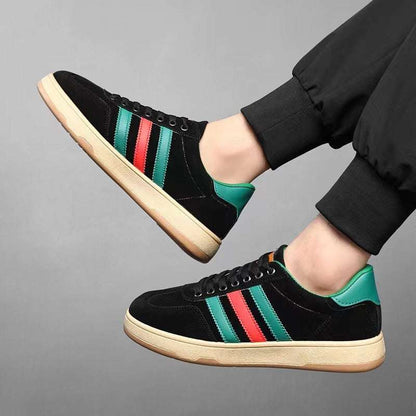 Black versatile casual sneakers with green and red stripes and beige sole worn with black pants